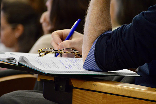 image of person taking notes with glasses on their notebook