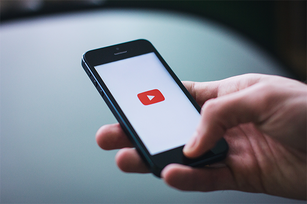 a hand holding a phone looking at the Youtube logo