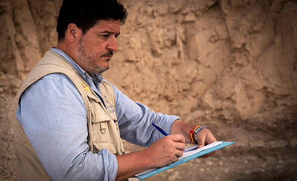 Antonio Morales standing outside writing on a clipboard.