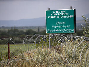 A warning sign is pictured behind a wire barricade erected by Russian and Ossetian troops along Georgia's de-facto border with its breakaway region of South Ossetia in 2015 REUTERS
