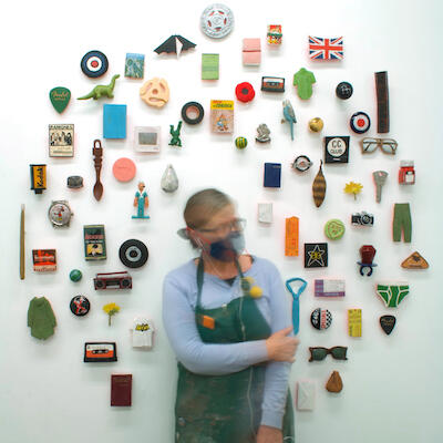 Pattie Chalmers in front of installation of objects on the wall