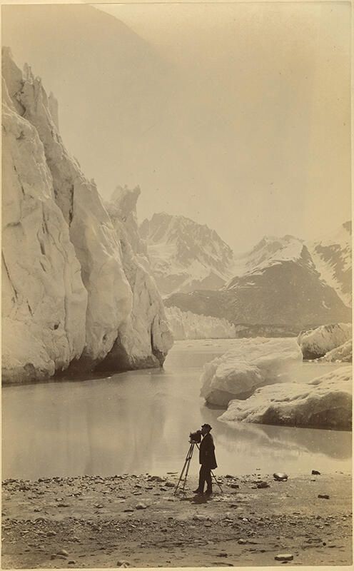 man with an antique camera standing next a lake