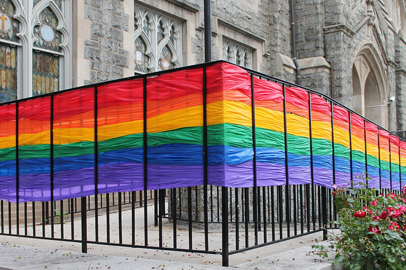 Rainbow banner woven into fence surrounding a church