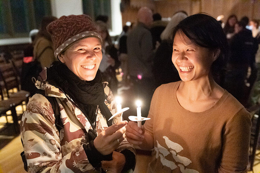 Two grinning HDS students holding lit candles