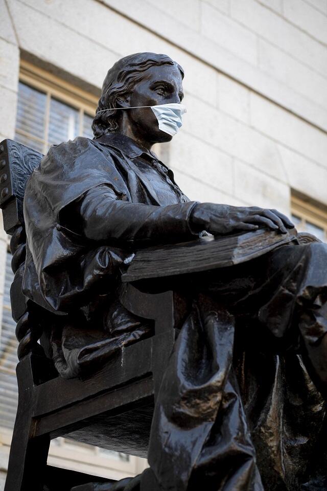 The John Harvard statue wearing a mask