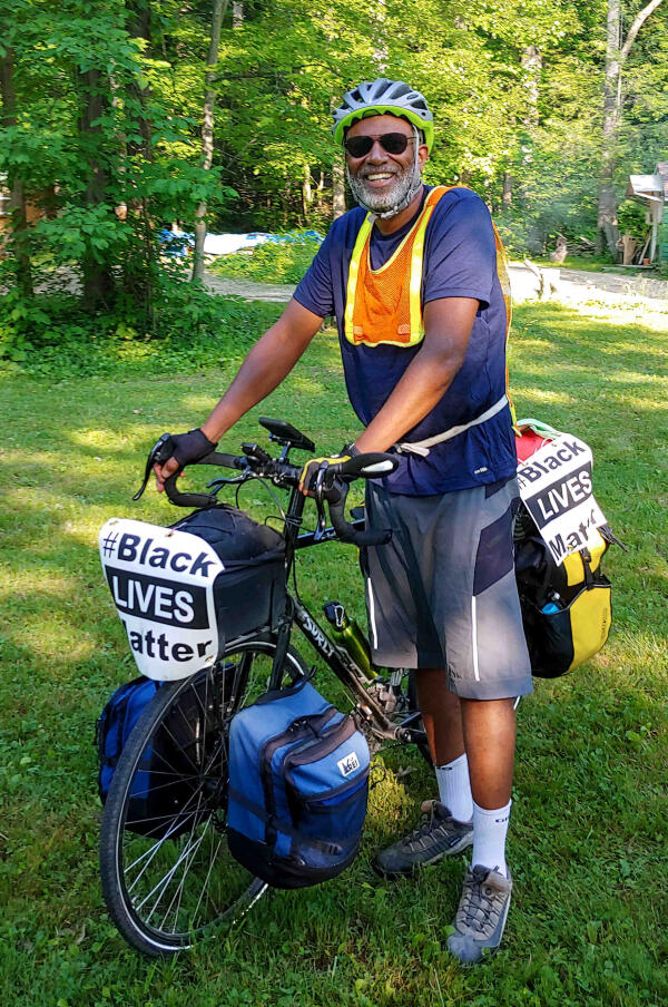 African American man with a bike and a sign that says black lives matter.