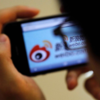 A man looks over at Weibo, a Chinese microblogging app