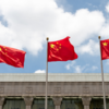 Three Chinese flags fly above a building