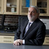 A photo of Professor Nocera leaning against a lab bench in his lab