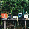 A photo of a row of mailboxes of different colors and shapes
