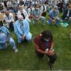 Diverse group of medical professionals on one knee with heads bowed on grass. Image by Boston Globe/Getty Images