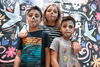 3 kids with sugar skull face paint pose in front of illustrated background.